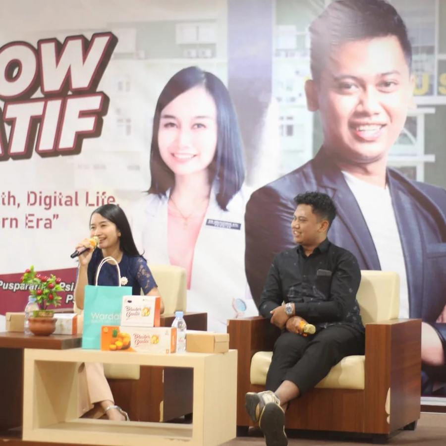 Narasumber talkshow berbicara dengan latar spanduk acara